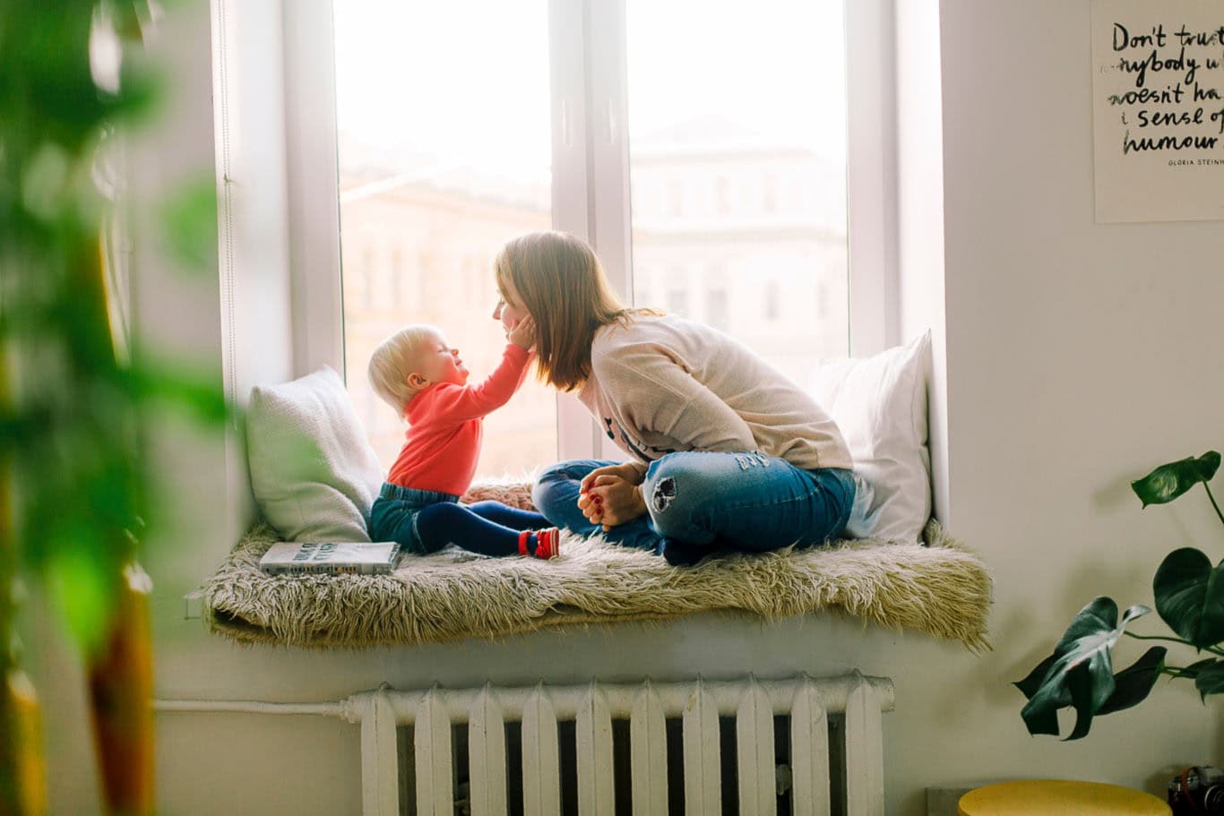 A baby and her mother play on the couch.