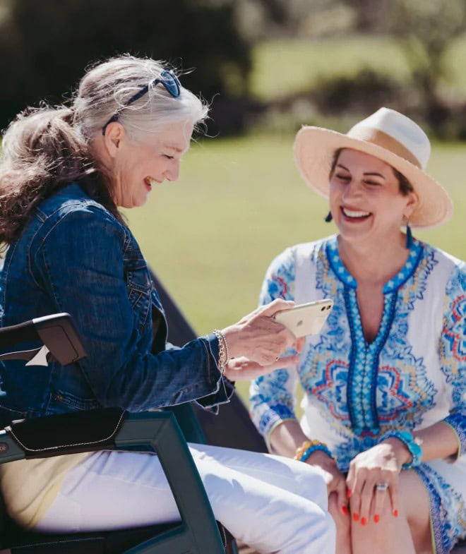 Two Elderly ladies sitting in park on phone